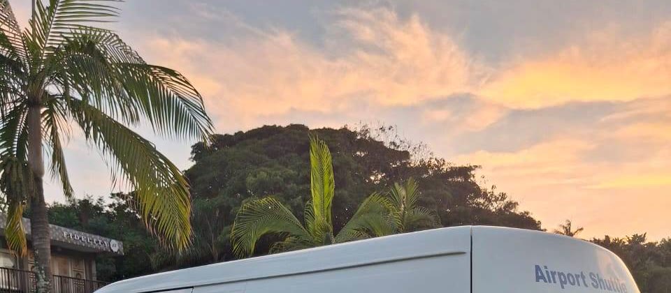 Palms and a sunset sky over Ballito, with the roof of the Dolphin Coast mini-bus in the foreground